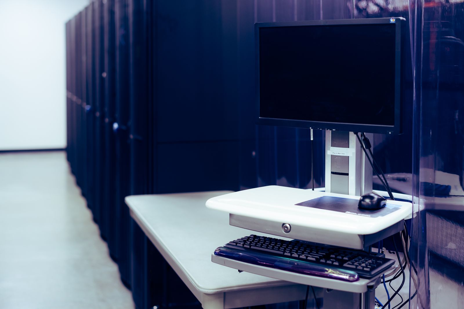 A quiet server room aisle lined with black racks