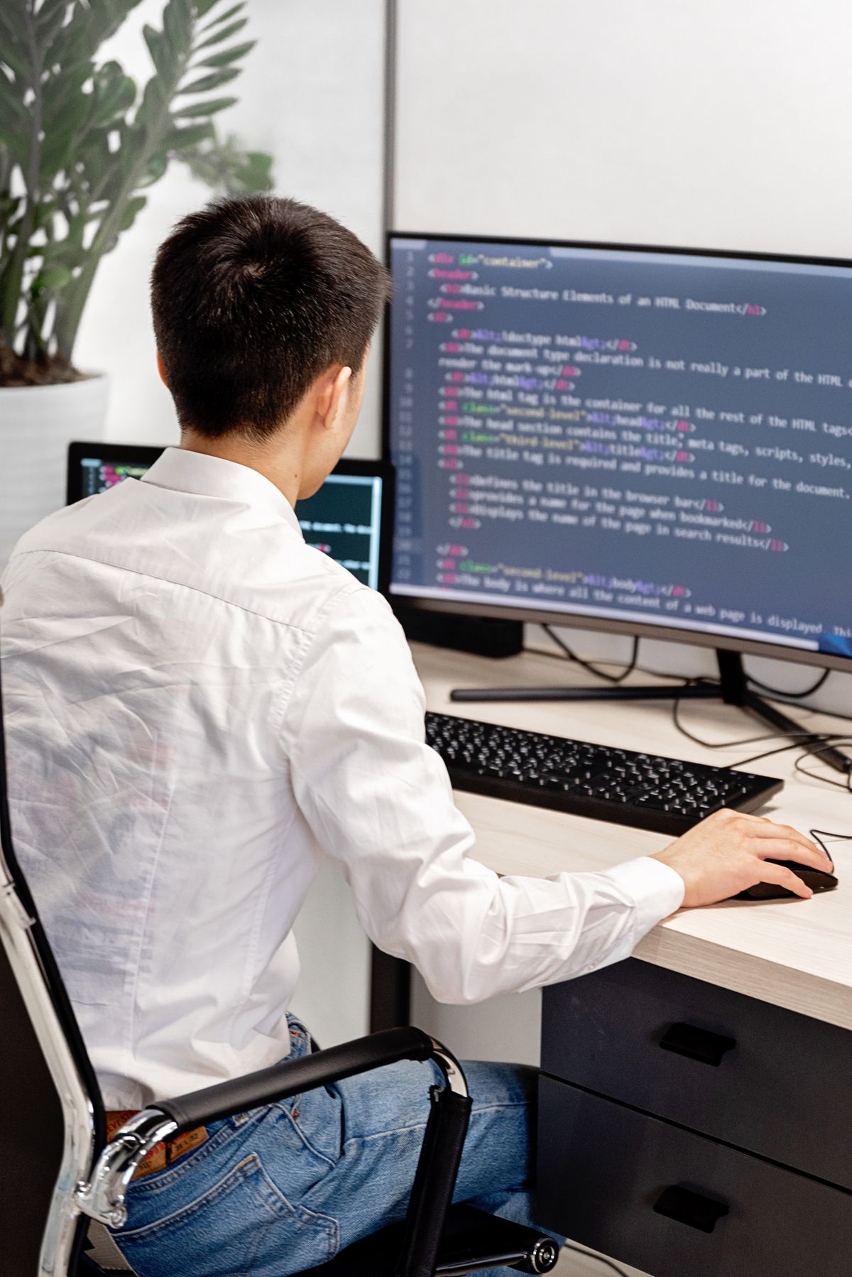 A developer reading highlighted code on a large monitor